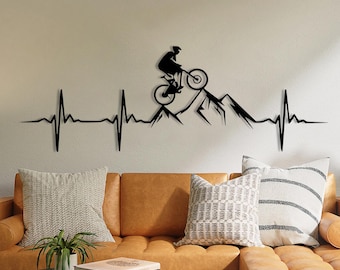 May include: A tan leather sectional sofa with a black coffee table in front of it. The wall behind the sofa has a black silhouette of a mountain range with a person riding a mountain bike, and a black and white heartbeat line.