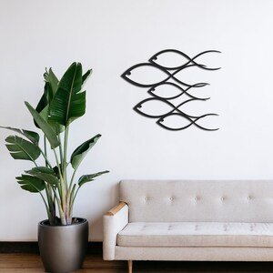 May include: Black metal wall art depicting a school of fish in a minimalist style. The fish are arranged in a layered pattern, creating a dynamic and modern design.
