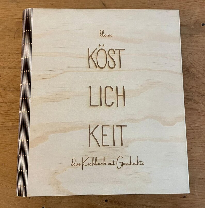 May include: A wooden cookbook with the title "kleine KOSTLICHKEIT" and the text "das Kochbuch mit Geschichte" on the cover.