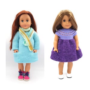 May include: Two dolls dressed in handmade crochet outfits. One doll wears a light blue dress with a matching scarf and pink and blue trainers. The other doll is in a purple dress with a crochet top and white shoes. Both dolls have long hair.