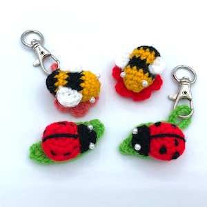 Può includere: Quattro portachiavi all'uncinetto con un design di coccinella, un'ape e due diversi design di fiori. I portachiavi sono realizzati con filato rosso, giallo, nero, bianco e verde.