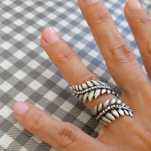 May include: A silver ring with a leaf design. The ring is adjustable and can be worn on any finger.