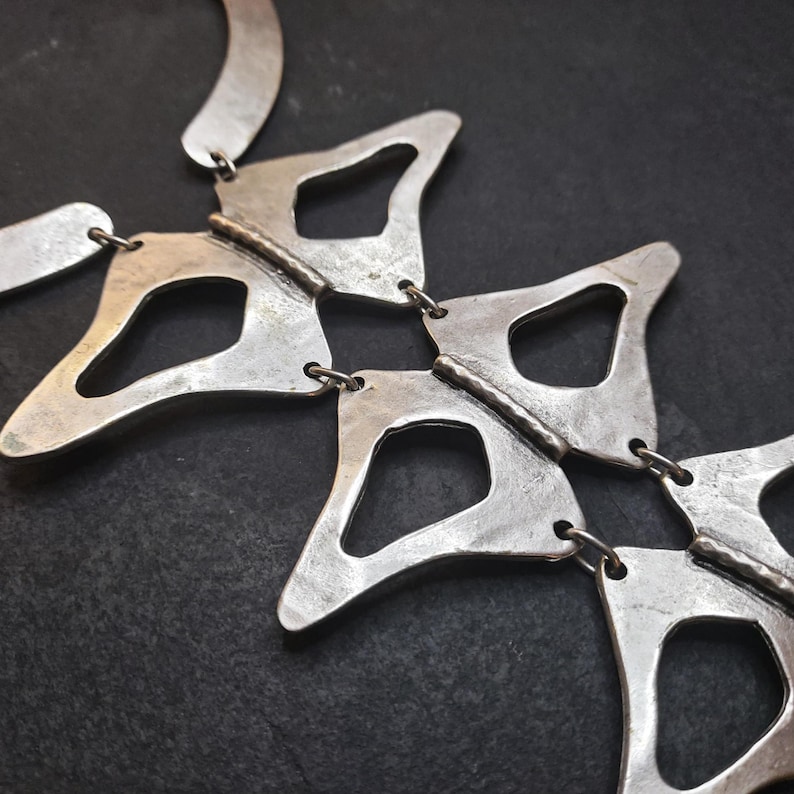 Anatomical silver statement necklace close up on model brick wall, handmade sculptural silver plated geometric necklace chest detail, wearable art jewelry by Gozemre Atelier