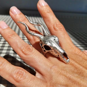 Może przedstawiać: Biały ceramiczny kubek z czarnym uchwytem i napisem "But First, Coffee" pogrubioną, czarną czcionką. Kubek jest umieszczony na neutralnym tle, podkreślając jego prosty design.