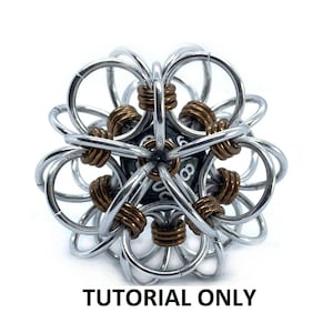 May include: A silver and bronze metal chainmaille ball with a black six-sided die in the centre. The ball is made of many small interlocking rings. "TUTORIAL ONLY" is written below the ball.