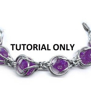 May include: A silver chain bracelet with purple dice charms. The dice are faceted and have white numbers. The bracelet is made with a woven chain pattern.