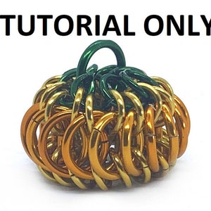 May include: A small pumpkin-shaped ornament made of gold and green metal rings. The ornament is a chainmaille creation.