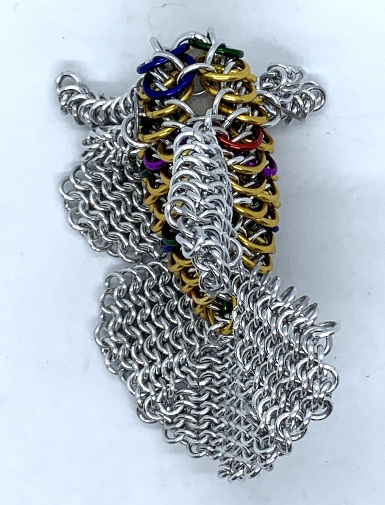 May include: A silver chainmail dragon sculpture with a colorful, multi-layered, gold, green, blue, purple, and red chainmail tail.