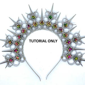 May include: A silver metal crown with a halo design, featuring pointed spikes and iridescent, colourful gems. The text "TUTORIAL ONLY" is printed on the crown. The crown has a headband base.