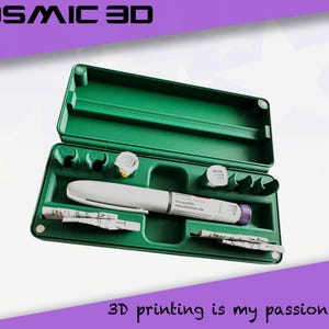 May include: Green plastic case containing a white and gray medical pen, small vials, and paper inserts. The case is open, revealing the contents. Text at the top reads "COSMIC 3D" and at the bottom "3D printing is my passion".