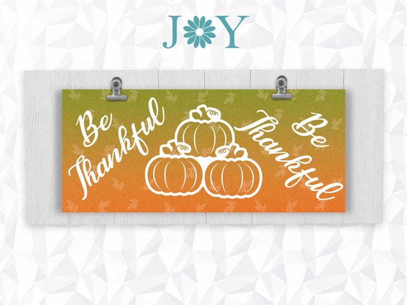 May include: A banner with an orange and green gradient background. The banner has the text "Be Thankful" on each side and a white silhouette of three pumpkins in the center.