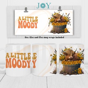 May include: A white ceramic mug with a brown Highland cow in a pot of yellow flowers. The mug has the text "A LITTLE MOODY" in orange and brown letters.