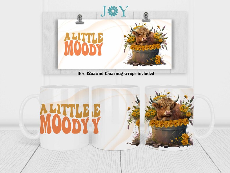 May include: A white ceramic mug with a brown Highland cow in a pot of yellow flowers. The mug has the text "A LITTLE MOODY" in orange and brown letters.
