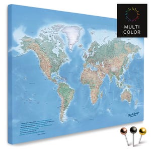 Peut inclure: Une carte du monde imprimée sur toile avec un fond bleu clair. La carte présente les continents et les pays en différentes couleurs. Le texte "MULTI COLOR" est dans un carré noir. Trois punaises sont en bas à droite.