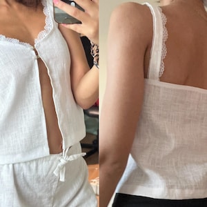 May include: White linen tank top with a lace trim and a button down front. The tank top is paired with matching linen shorts.