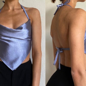 Op de afbeelding: Een lichtblauw satijnen haltertop met een cowl neck en een strik aan de achterkant.