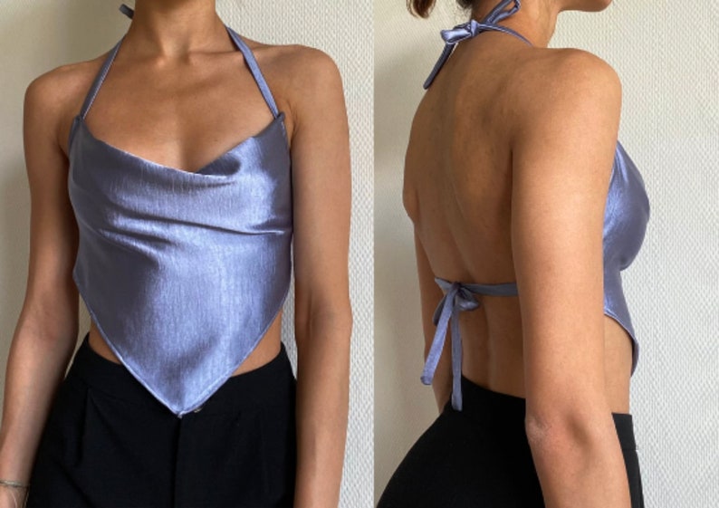Op de afbeelding: Een lichtblauw satijnen haltertop met een cowl neck en een strik aan de achterkant.