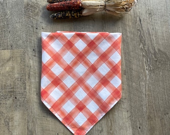May include: Orange and white checkered table runner with a diagonal pattern. The runner is made of fabric and has a frayed edge.