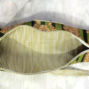 May include: Open, rectangular bag with a tiger print exterior in shades of brown, green, and black. The interior features vertical stripes in light green and white. A white zipper runs along the top edge.