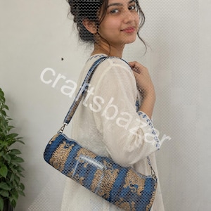 May include: A cylindrical yoga mat bag with a blue and tan pattern, a zip closure, and a shoulder strap. The bag is made of woven fabric. The text "craftsbazar" is visible on the image.
