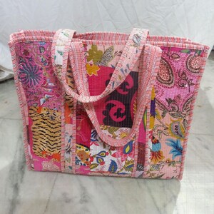 Könnte beinhalten: Eine Patchwork-Tragetasche mit verschiedenen Blumen- und Tiermotiven in Rosa-, Rot- und Orangetönen. Die Tasche hat zwei Griffe und eine rechteckige Form.