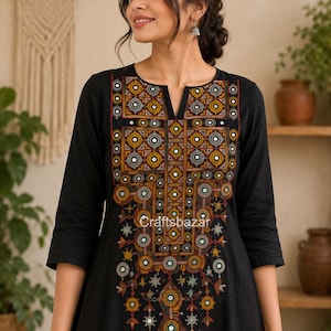 May include: A black long-sleeved tunic featuring a prominent V-neckline and intricate, multi-colored geometric embroidery down the front. The design incorporates small circular mirror accents throughout the pattern, with the text Craftsbazar visible.