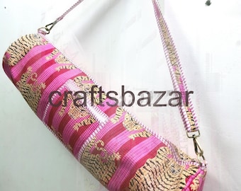 May include: A cylindrical yoga mat bag with a pink and gold tiger stripe pattern. The bag has a matching shoulder strap and metal hardware. The text "craftsbazar" is printed on the bag.