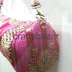 May include: A pink and tan quilted duffel bag with a striped and animal print pattern. The bag has a matching strap and the text "craftsbazar" is visible on the side.