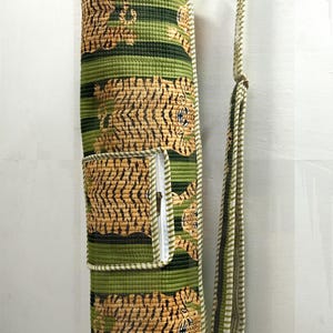 May include: A green and tan yoga mat bag with a tiger print design. The bag has a zippered pocket and a shoulder strap. The bag is cylindrical and made of quilted fabric.