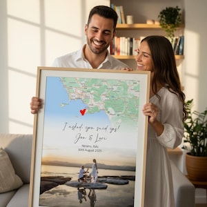 May include: A framed print with a map and a photo of a couple. The map has a heart marking a location. Text reads "I asked, you said yes! Jon & Lori, Nerano, Italy, 30th August 2025". The frame is light-coloured.