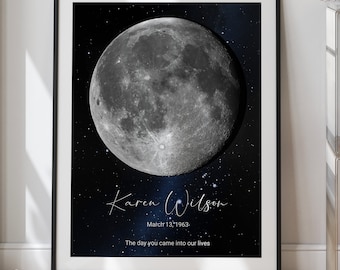 May include: A black and blue moon phase print with the name "Karen Wilson" and the date "March 13, 1963." The text below the date reads "The day you came into our lives."