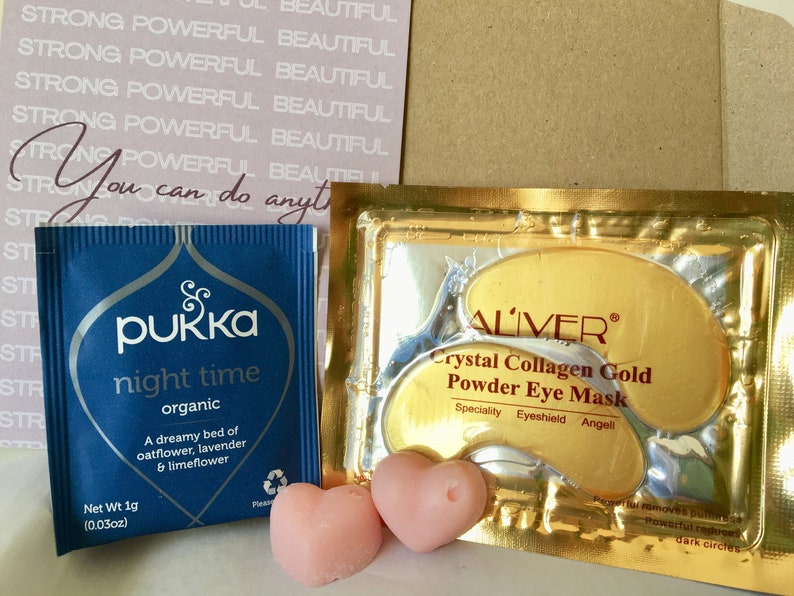 May include: A blue tea bag package with the text "pukka night time organic" and a pink heart-shaped candle. A gold package with the text "ALIVER Crystal Collagen Gold Powder Eye Mask" and two gold eye masks.