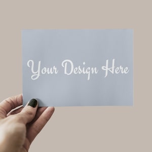 以下が含まれることがあります： 白い文字で「Your Design Here」と書かれた薄い青色のカードを手に持っている