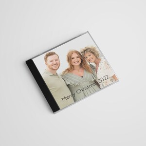 May include: A CD case with a photo of three people smiling. The text "Merry Christmas 2022" is printed on the case.