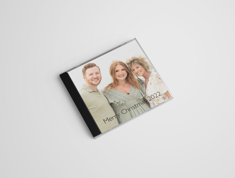 May include: A CD case with a photo of three people smiling. The text "Merry Christmas 2022" is printed on the case.