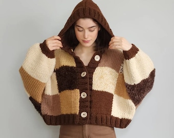 May include: A brown, beige, and cream knitted cardigan with a hood and button closure. The cardigan has a checkered pattern.