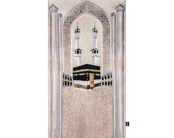 May include: A beige prayer rug featuring an illustration of the Kaaba in Mecca, with two minarets and an arched design. The rug has a fringed border and a patterned background, suitable for Islamic prayer.