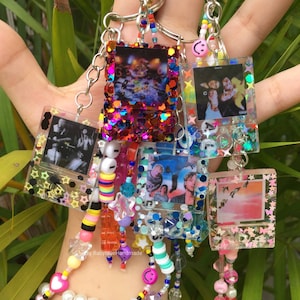 Puede incluir: Un conjunto de seis llaveros de resina coloridos con diferentes imágenes y purpurina incrustada en el interior. Cada llavero tiene una cadena plateada y una variedad de cuentas de colores.