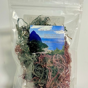 May include: A clear plastic resealable pouch containing dried sea moss in shades of green and reddish-purple. A label on the front features a landscape image of St. Lucia and the text: MG Windward Trading, Premium Quality and Wild Harvested From the Shores of St. Lucia, All Natural Sea Moss.