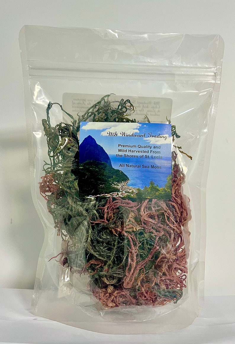 May include: A clear plastic resealable pouch containing dried sea moss in shades of green and reddish-purple. A label on the front features a landscape image of St. Lucia and the text: MG Windward Trading, Premium Quality and Wild Harvested From the Shores of St. Lucia, All Natural Sea Moss.
