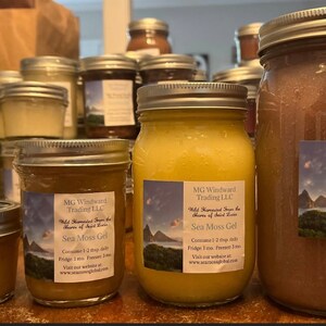 May include: A close-up of three glass jars filled with a yellow and brown gel. The jars have labels that read "MG Windward Trading LLC Wild Harvested Sea Moss from the Shores of Saint Lucia Sea Moss Gel Consume 1-2 tbsp daily Fridge: 1 mo Freezer: 1 mo Visit our website at www.seamosglobal.com".