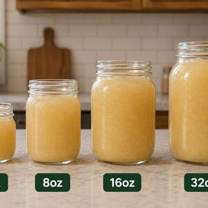 Pode incluir: Quatro frascos de vidro transparente cheios de um l&iacute;quido amarelo claro, dispostos em fila do menor para o maior. Os frascos est&atilde;o etiquetados com texto indicando as suas capacidades de 4oz, 8oz, 16oz e 32oz, mostrando a progress&atilde;o.