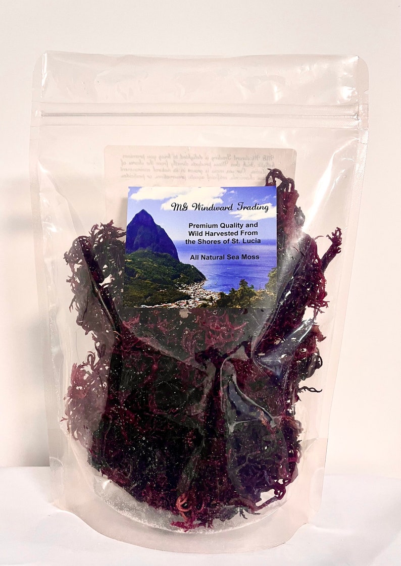 May include: A clear resealable plastic pouch containing dark purple dried sea moss. A label features the text M&G Windward Trading, Premium Quality and Wild Harvested From the Shores of St. Lucia, All Natural Sea Moss, and a landscape image.