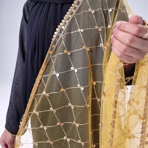 May include: A yellow sheer scarf with gold sequins arranged in a grid pattern. The scarf has a gold fringe border.
