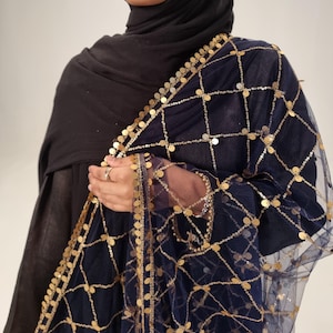 May include: A navy blue sheer scarf with gold coin embellishments. The scarf has a delicate net-like texture and is adorned with gold coins that are evenly spaced throughout the fabric.