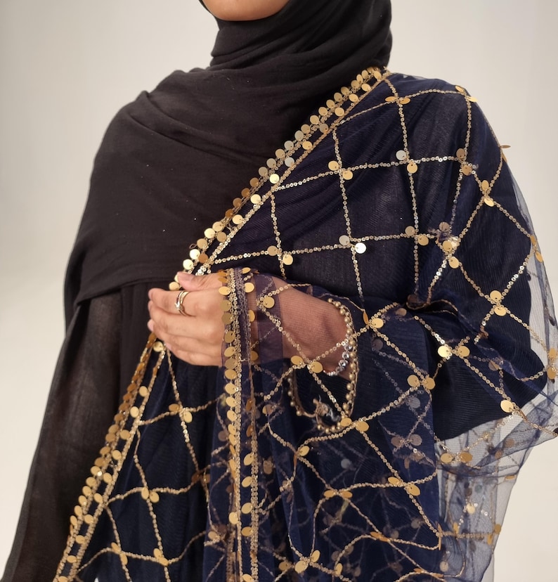 May include: A navy blue sheer scarf with gold coin embellishments. The scarf has a delicate net-like texture and is adorned with gold coins that are evenly spaced throughout the fabric.