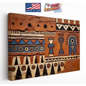 May include: A rectangular canvas wall art piece featuring a textured, terracotta-colored surface with painted geometric patterns in black, white, and blue. The design includes rows of dots, triangles, and stylized vessel shapes across the surface.