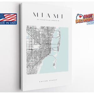 May include: A rectangular wall art print featuring a black and white street map of Miami, Florida. The design includes the text MIAMI, the coordinates 25.775163° N 80.208615° W, and the words UNITED STATES, set against a pale blue water background.