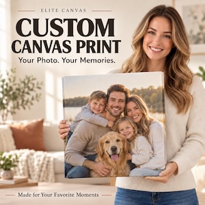 A woman is holding a large canvas print of a family portrait, smiling and posing for the camera.