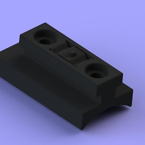 Puede incluir: Un componente negro y rectangular con dos orificios circulares y una sección central elevada. El objeto tiene un diseño escalonado y parece estar hecho de un material sólido y mate. El fondo es de color lila claro.